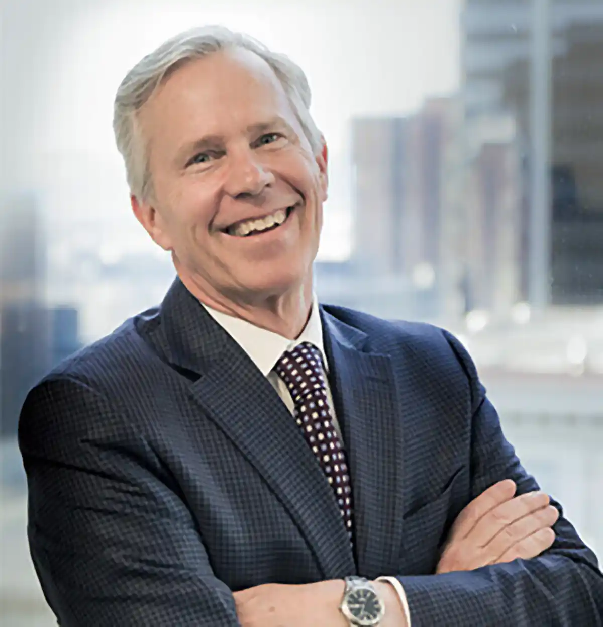 W. Dan Mahoney smiling, arms crossed, downtown Denver behind him